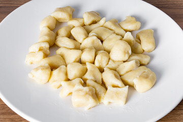 BAKED GNOCC IN A WHITE PLATE ON A WOODEN BACKGROUND