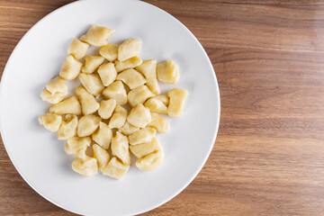 BAKED GNOCC IN A WHITE PLATE ON A WOODEN BACKGROUND.
