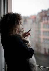 Woman with cat standing near the open window