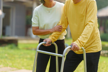 Elderly Asian couple and wife caring for their family enjoying retirement together in park. Old Caregiver people take close care while using walking cane stick.