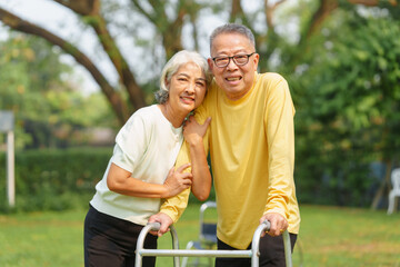 Elderly Asian couple and wife caring for their family enjoying retirement together in park. Old Caregiver people take close care while using walking cane stick.