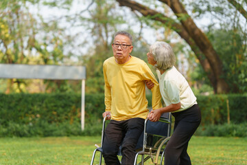 Fototapeta na wymiar Elderly Asian couple and wife caring for their family enjoying retirement together in park. Old Caregiver people take close care while using walking cane stick.