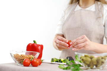 Beautiful young woman preparing vegetable salad in the kitchen. Healthy food. Vegan salad Diet concept. Healthy lifestyle. Cook at home. Prepare food close-up, only hands, olives, tomato, cucumber