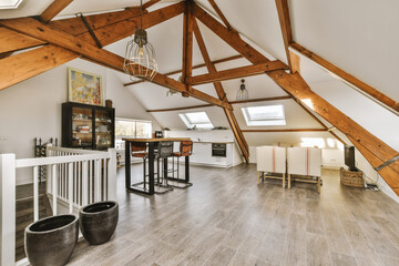 a living room and kitchen area in an attic style home with wood beams on the ceiling, white walls and hardwood flooring