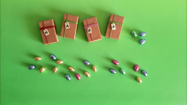 Easter stop motion. Funny greeting video. Concept of Easter egg hunting, gifts, traditions. Chocolate eggs in multi colored shiny wrapper are moving, packed in gift boxes with inscription Happy Easter