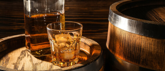 Glass and bottle of whiskey on wooden barrel