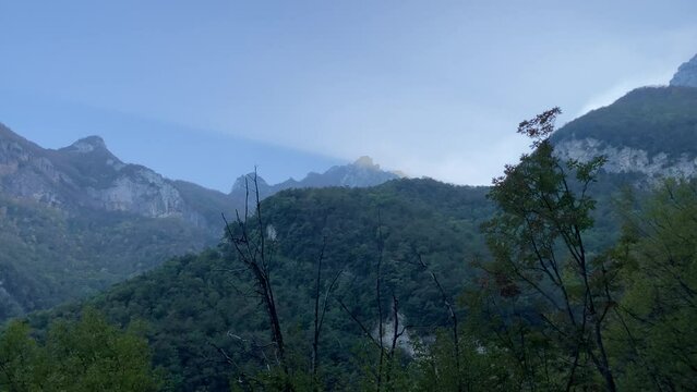 Majestic view at Sibillini mountains near Eremo di Soffiano (Sarnano) with their massive rocky ridges topped by abundant green vegetation interspersed with trees in the foreground under a cerulean sky