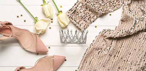 Beautiful tiara, female dress, shoes and roses on white wooden background. Prom concept © Pixel-Shot