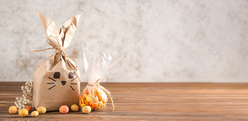 Easter bunny gift bag and candies on wooden table against light background