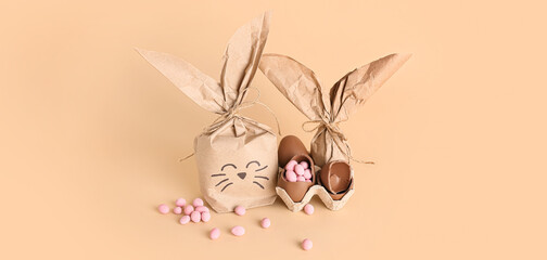 Easter bunny gifts, chocolate eggs and candies on beige background