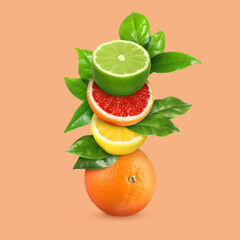 Stack of different fresh citrus fruits with green leaves on coral background