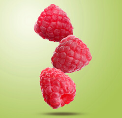 Fresh ripe raspberries falling on light green background