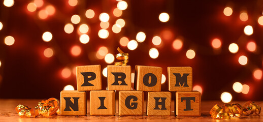 Wooden cubes with text PROM NIGHT on table against blurred lights