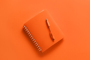 Fototapeta na wymiar Notebook with pen on orange background