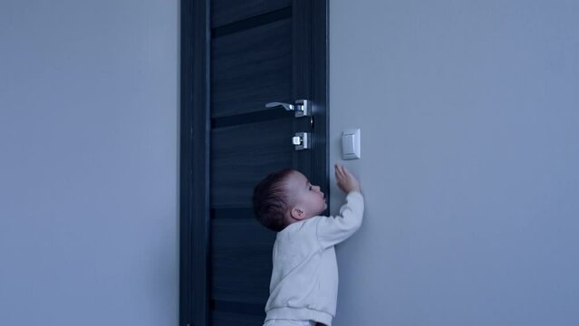 Happy Caucasian toddler playing with light switch. Baby boy turns off the illumination and walks away.