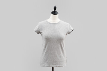 A gray short-sleeved t-shirt hangs on a white headless mannequin isolated by a light gray...