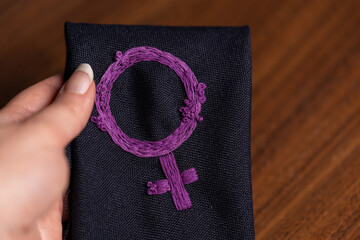 mano sosteniendo paño doblado con símbolo feminista bordado, como instrumento de protesta