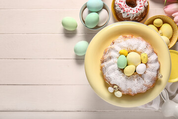 Composition with tasty Easter cakes and painted eggs on light wooden background