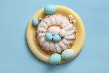 Plate with sweet Easter cake and painted eggs on color background