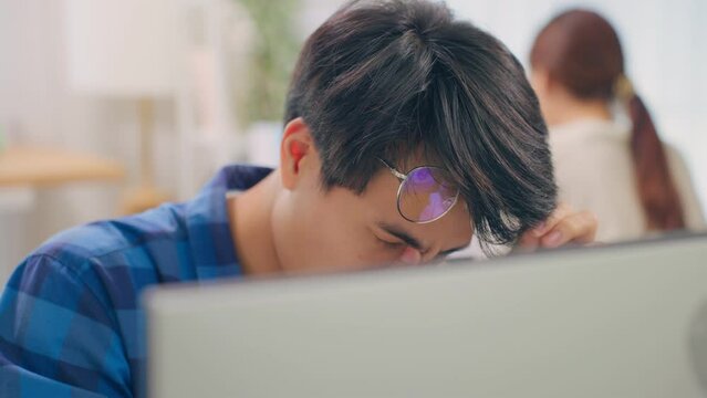 Exhausted Asain business man using laptop computer working in office.
