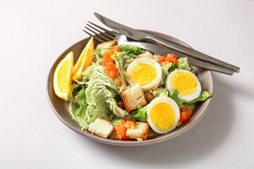 Plate of delicious salad with boiled eggs and salmon on grey background