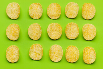 Many delicious potato chips on green background