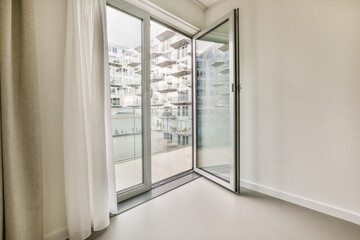 an empty room with sliding glass doors and white curtains on the window, looking out onto the...