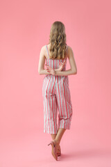 Young woman crossing fingers on pink background, back view