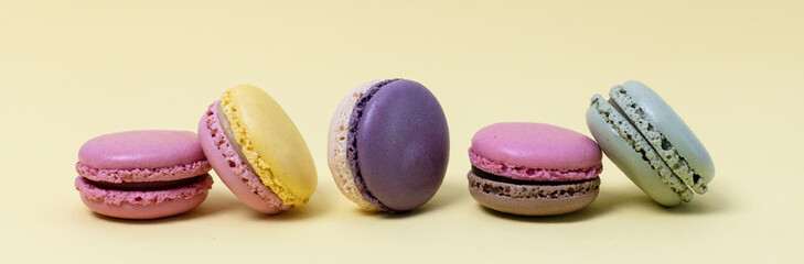Five colorful macaroons on a yellow background.