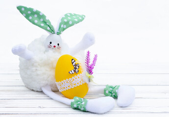 Easter bunny with yellow decorated egg on the wooden table.