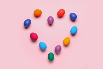 Heart made of colorful Easter eggs on pink background