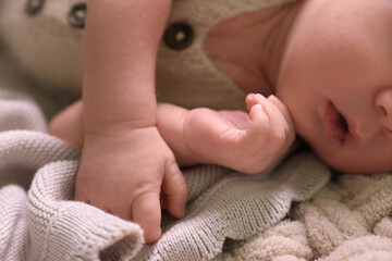 Cute newborn baby lying on beige crocheted plaid, closeup