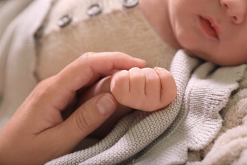 Mother and her newborn baby on beige crocheted plaid, closeup
