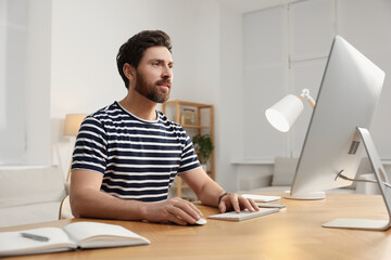 Home workplace. Man working with computer at wooden desk in room