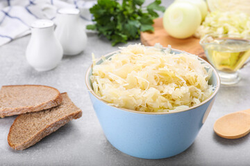 Bowl of tasty sauerkraut and ingredients on grey table