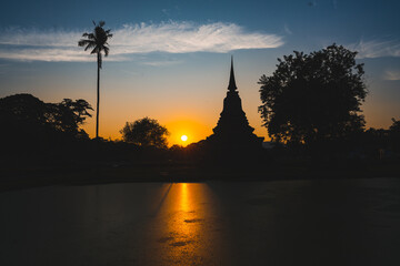 Fototapeta na wymiar Historic Town of Sukhothai temple park, Ancient Buddha Statue at sunset Sukhothai historical park, Mahathat Temple