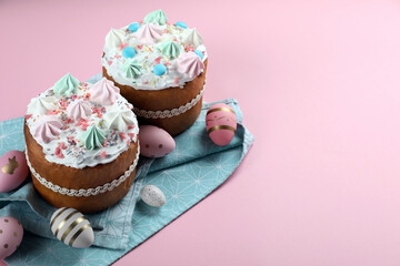 Traditional Easter cakes with meringues and painted eggs on pink background. Space for text