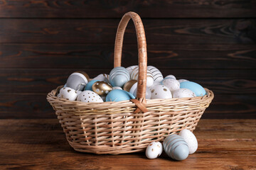 Wicker basket with festively decorated Easter eggs on wooden table