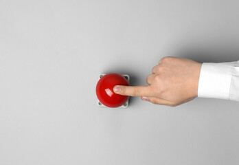 Man pressing red button of nuclear weapon on light gray background, top view with space for text....