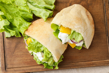 Delicious pita sandwiches with chicken breast and vegetables on wooden table, flat lay