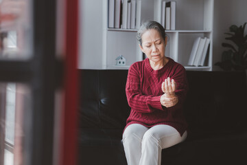 Senior woman sitting in the living room at home and showing body aches, aging sickness, body aches of elderly people, organ degeneration.