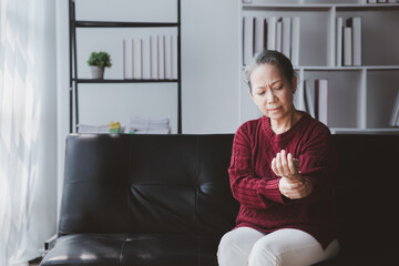 Senior woman sitting in the living room at home and showing body aches, aging sickness, body aches of elderly people, organ degeneration.