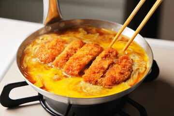 鍋で調理しているかつ丼