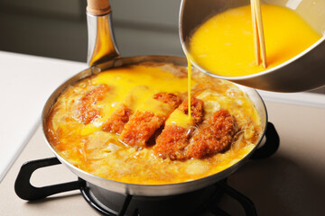 鍋で調理しているかつ丼