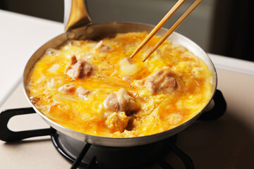 溶き卵を入れた親子丼の調理シーン