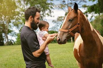 Father and little daughter touching horse.
