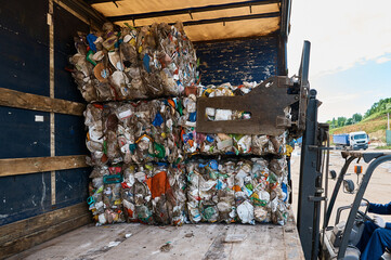 Forklift truck loads pressed plastic pack on shelf in yard
