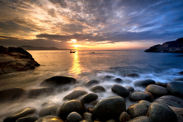 Fototapeta na wymiar Long exposure of sea and stones, beautiful sunrise in Quy Nhon city, Vietnam