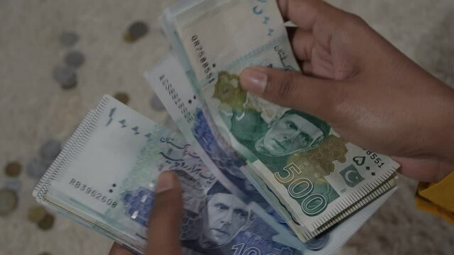 500 and 1000 per is being counted in the hands of a woman. Pakistan ruppee