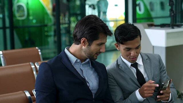 Two business men discussing stock market using mobile phone While waiting to board the plane at the airport.